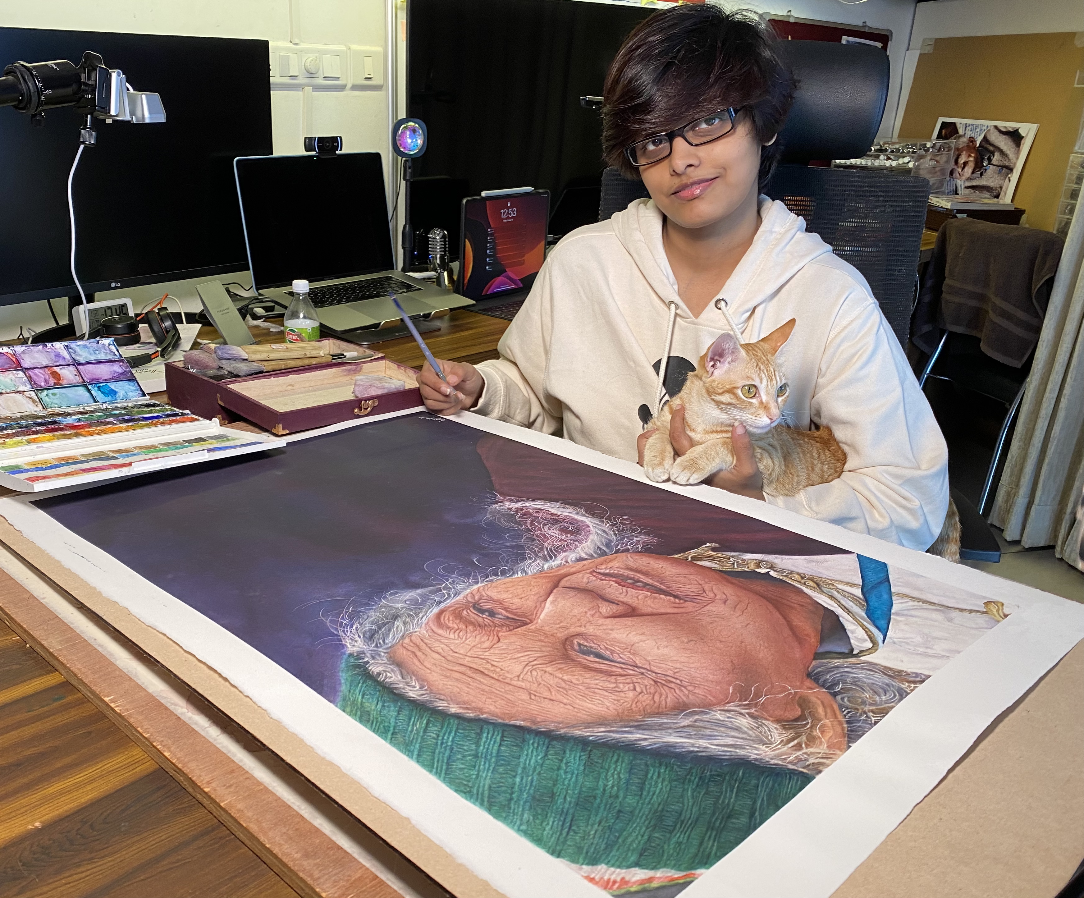 Madhubanti Mukherjee at her desk with her portrait painting Courage