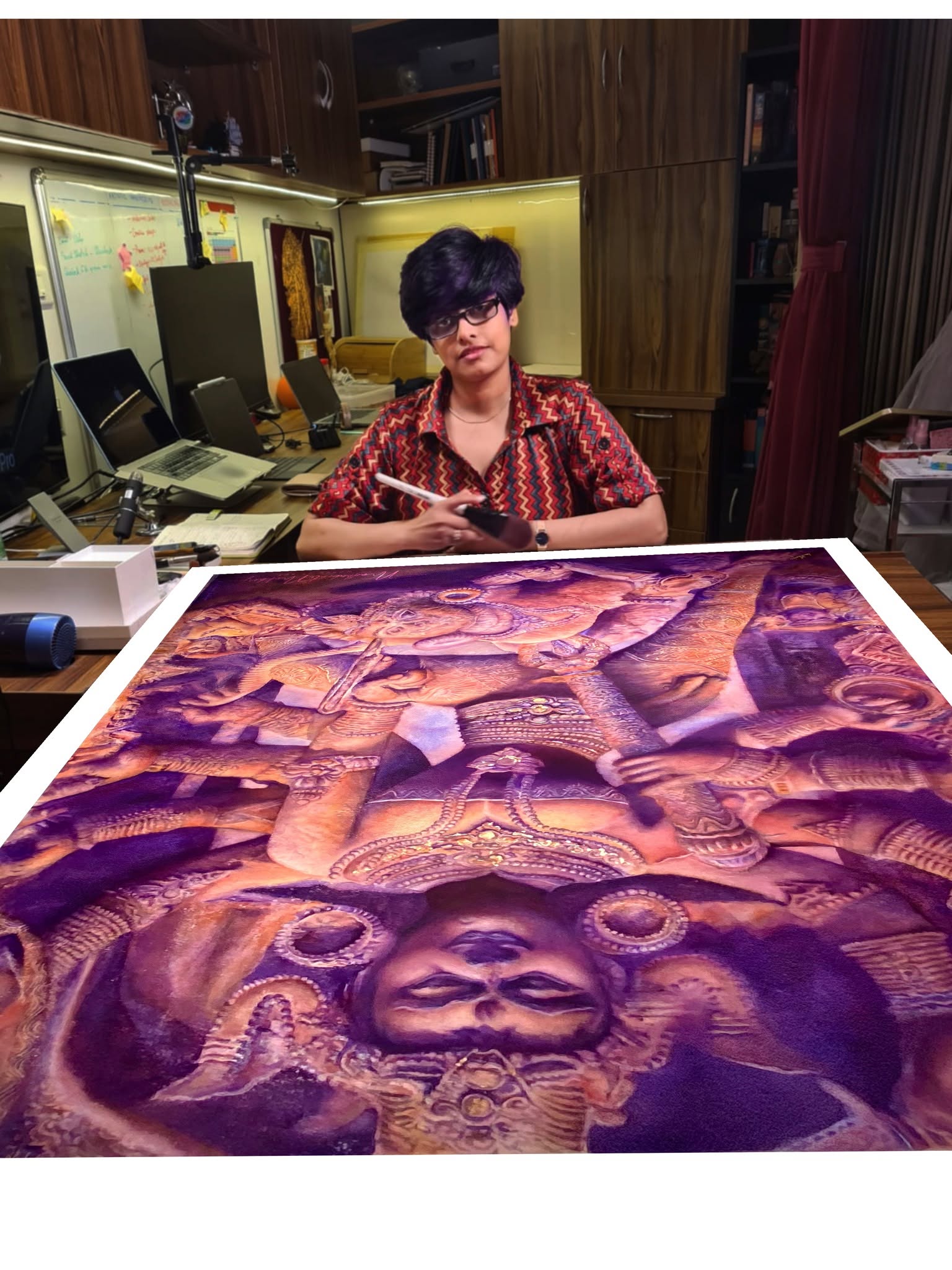 Madhubanti Mukherjee at her desk with her painting Mahishasuramardini