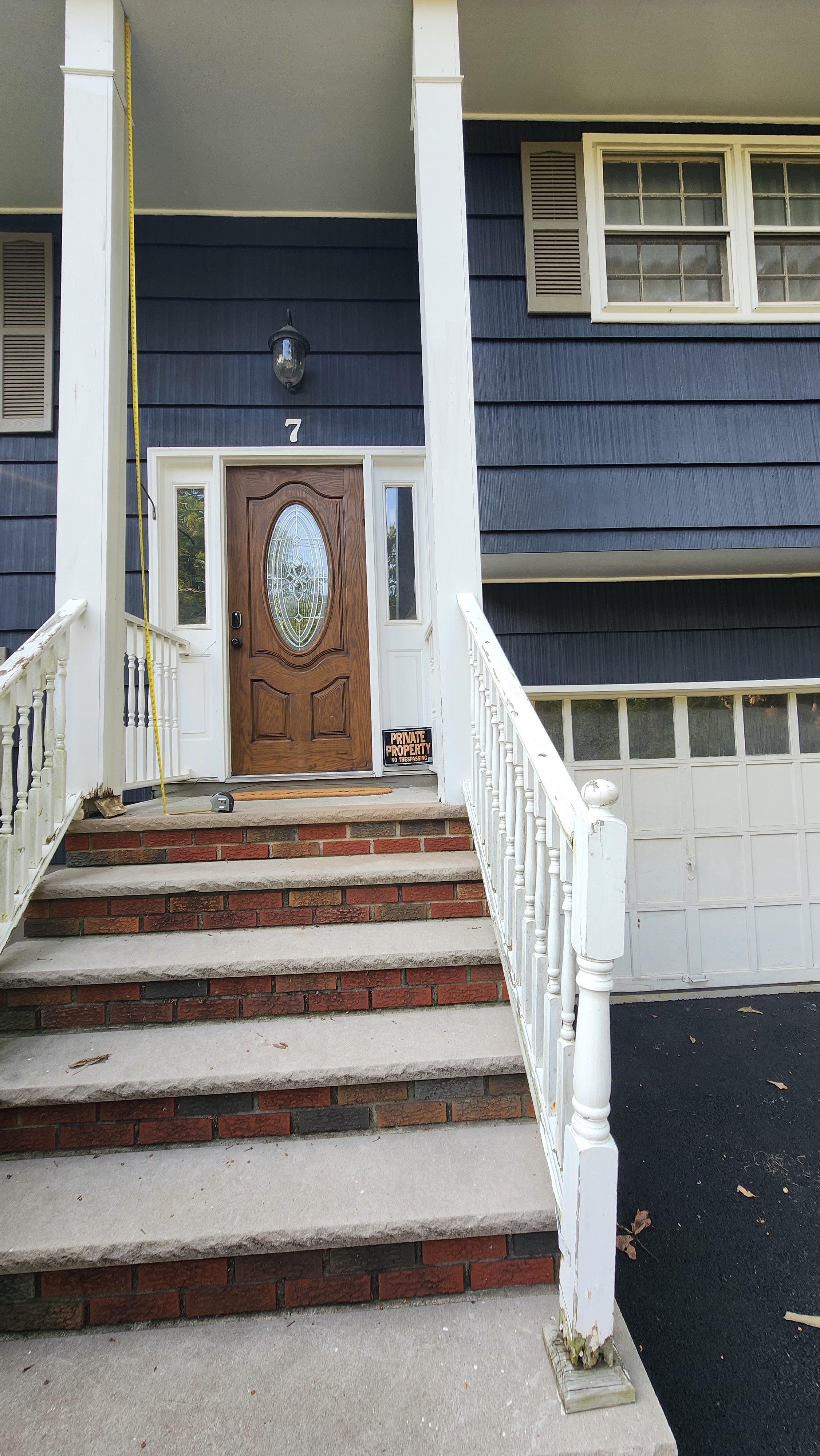 Front entrance of a house with a wooden door and white railing installed by Platinum Werx