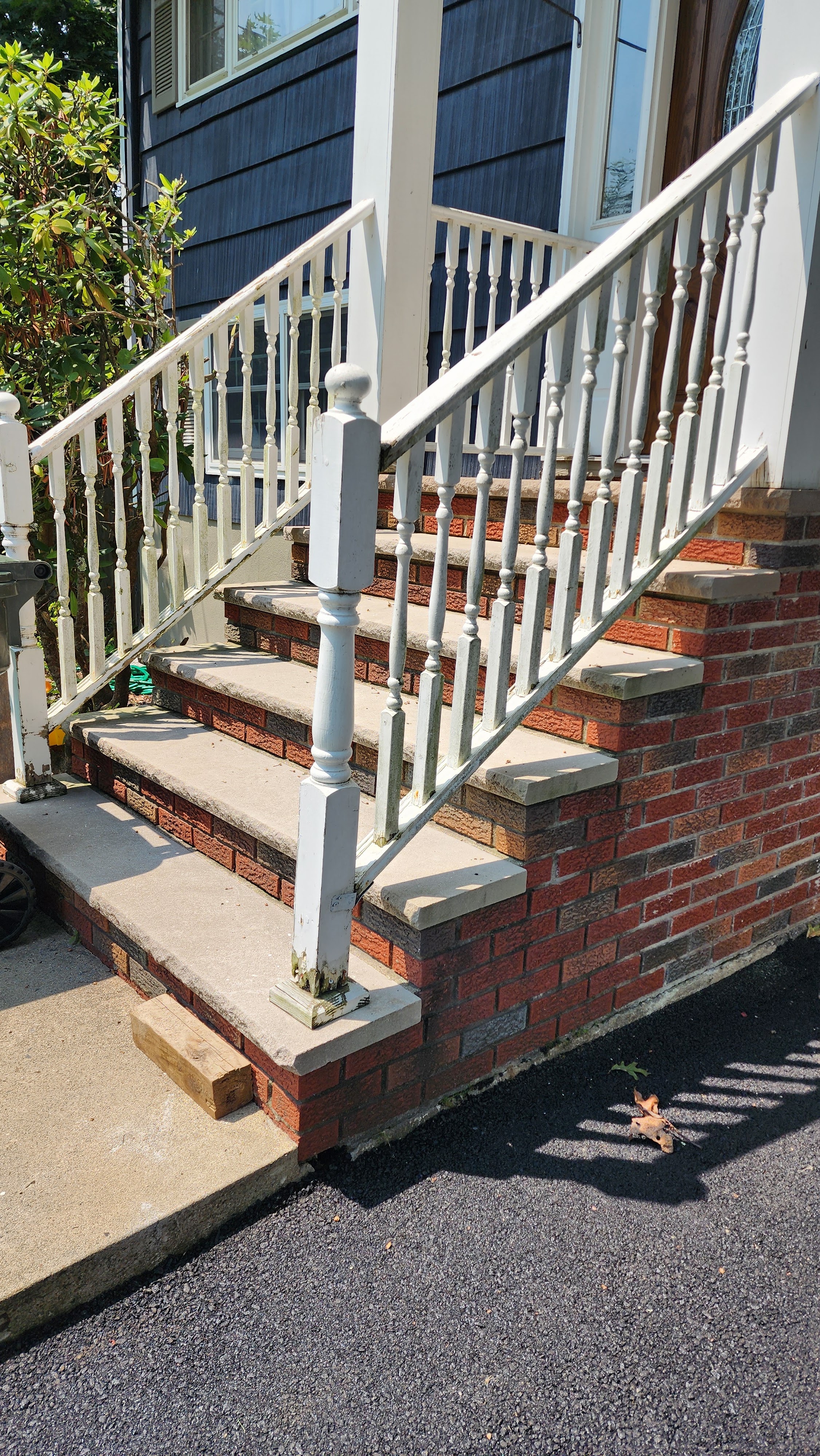 White wooden staircase with handrail leading up to the front entrance of a house, built by Platinum Werx