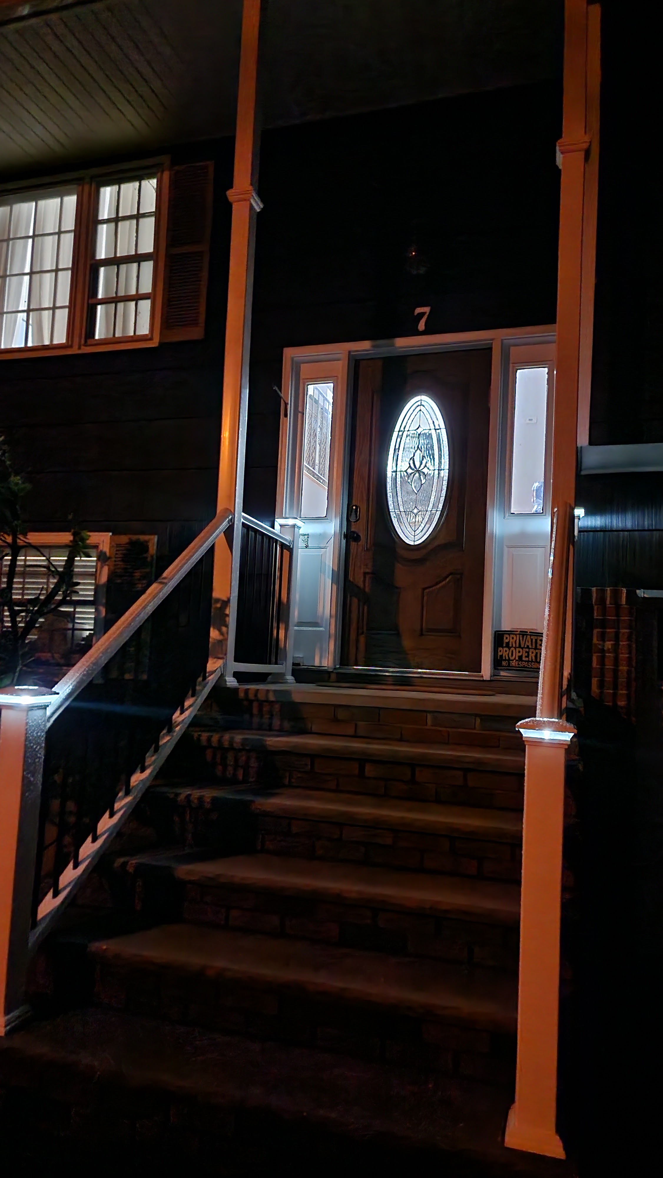 Front entrance of a house with a wooden door and an orange railing staircase built by Platinum Werx