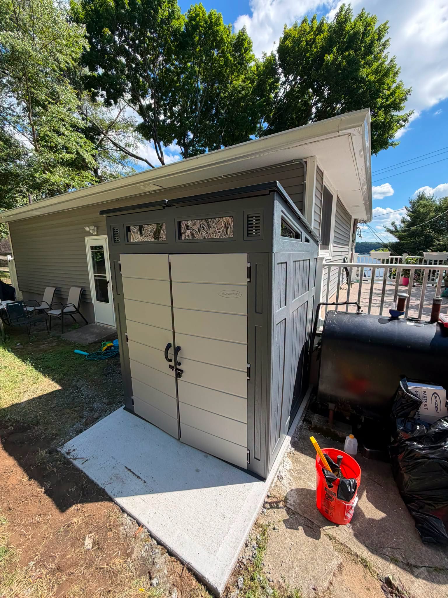Gray shed with two doors on a concrete pad in front of a house, built by Platinum Werx
