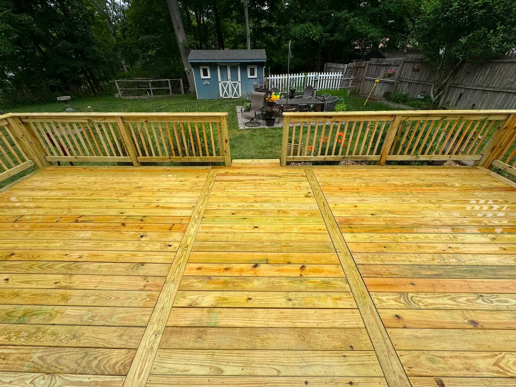 Finished wooden deck with railing in a backyard