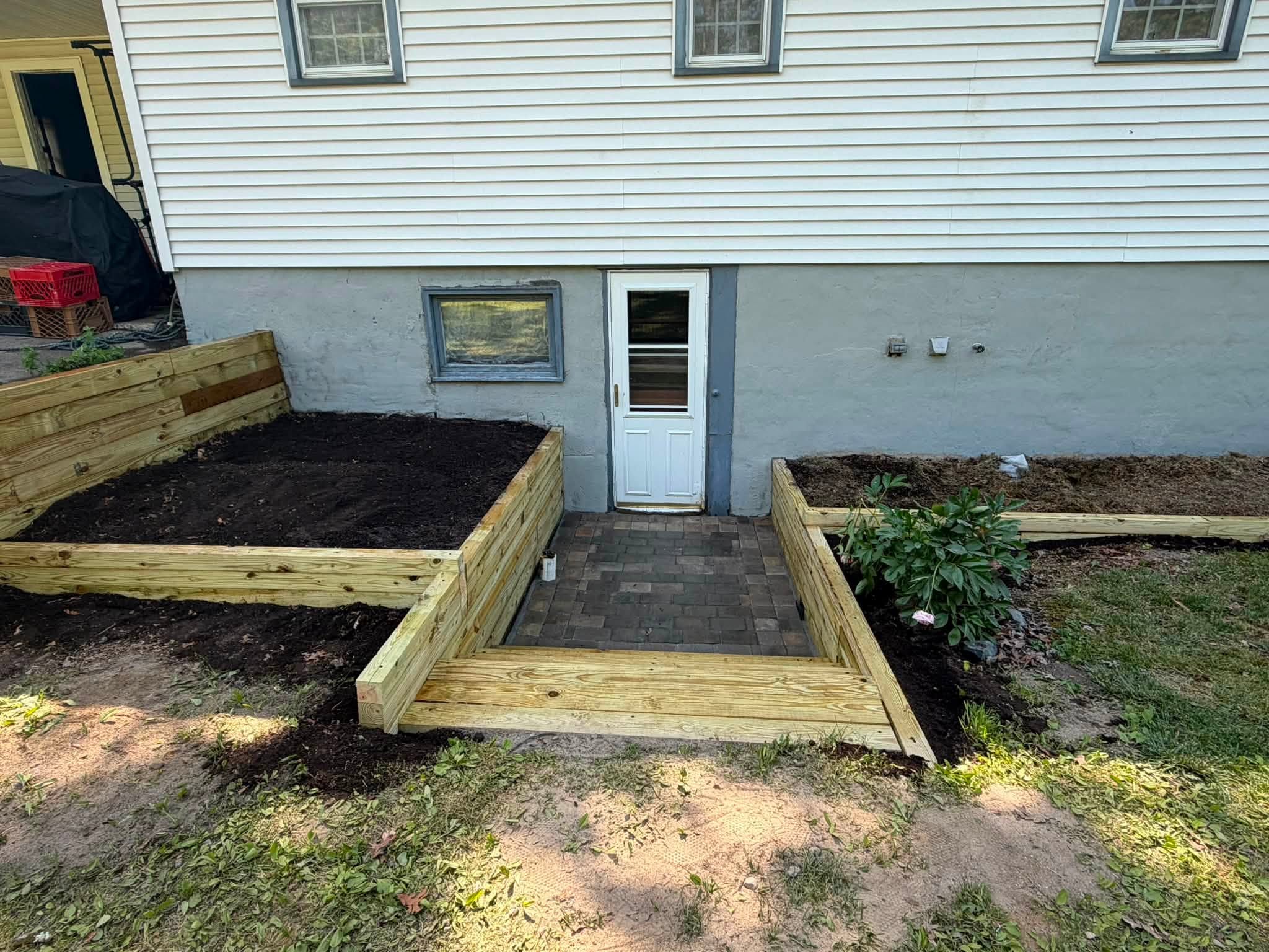 Raised bed with soil and a wooden ramp leading to an entrance door