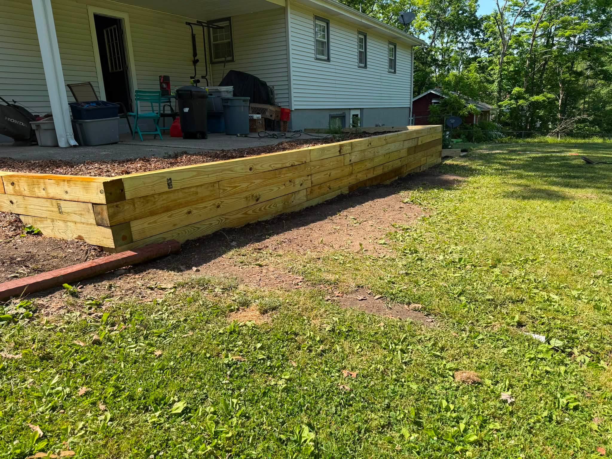 Wooden retaining wall in front of a house with a porch