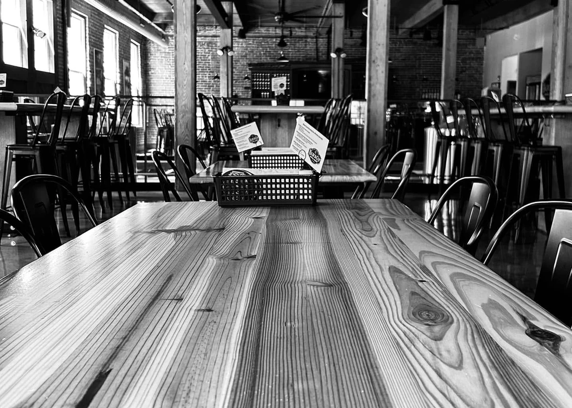 Reclaimed wood tables handcrafted from salvaged timber inside the Black Cap Brewing Company taproom, exposed brick walls and wood ceiling beams