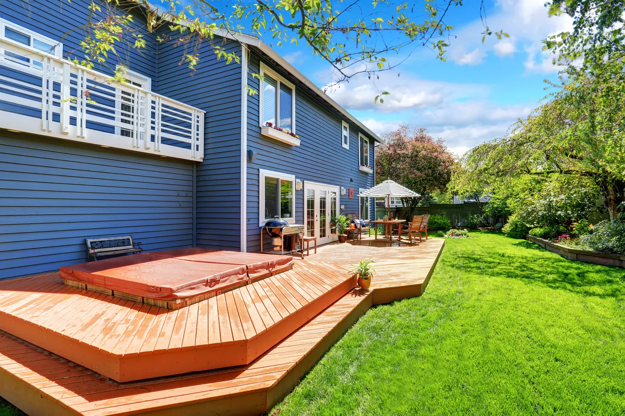 Backyard wood deck built beside a blue-sided home