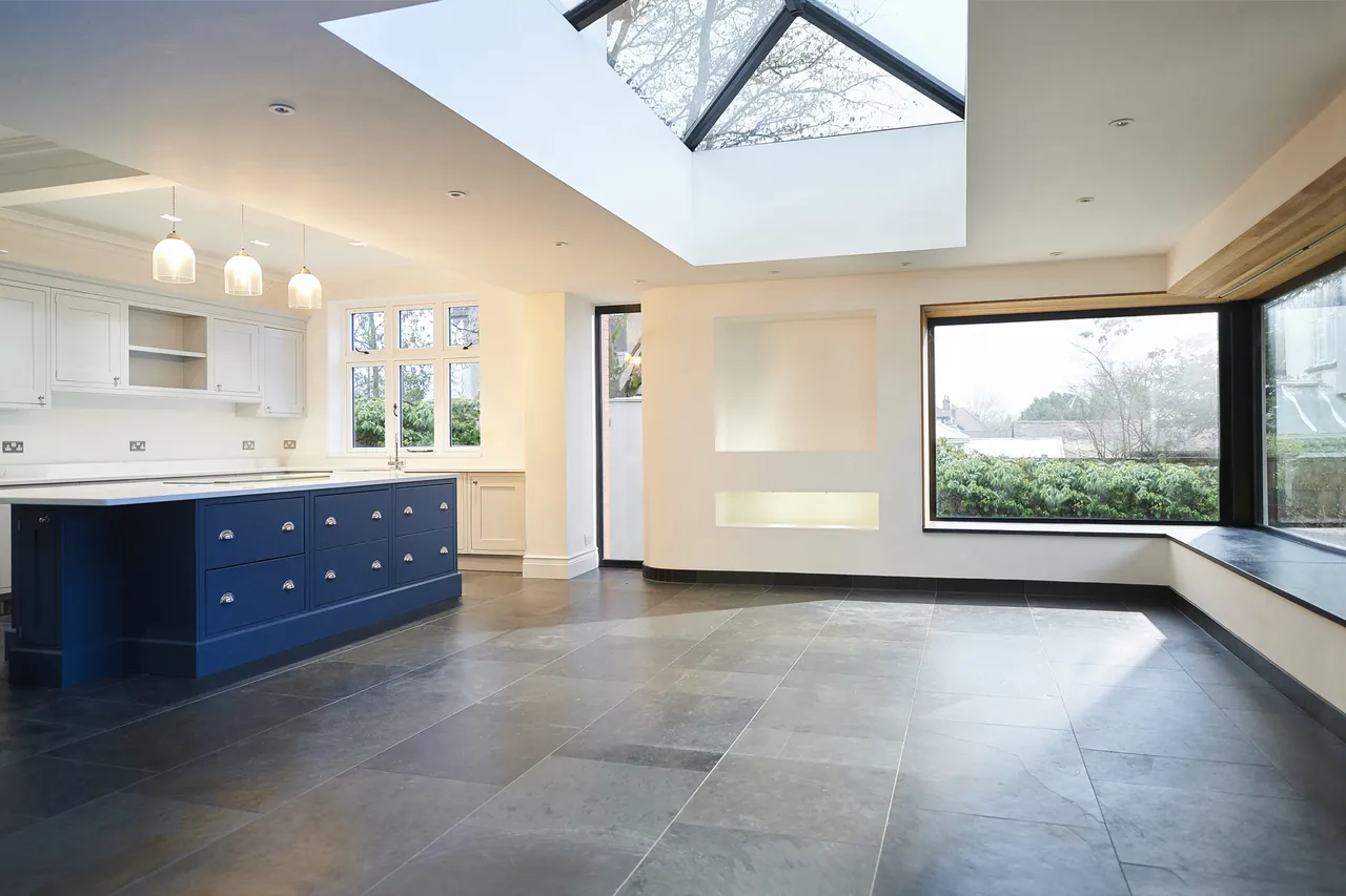 Open-plan kitchen remodel with a navy island and skylight