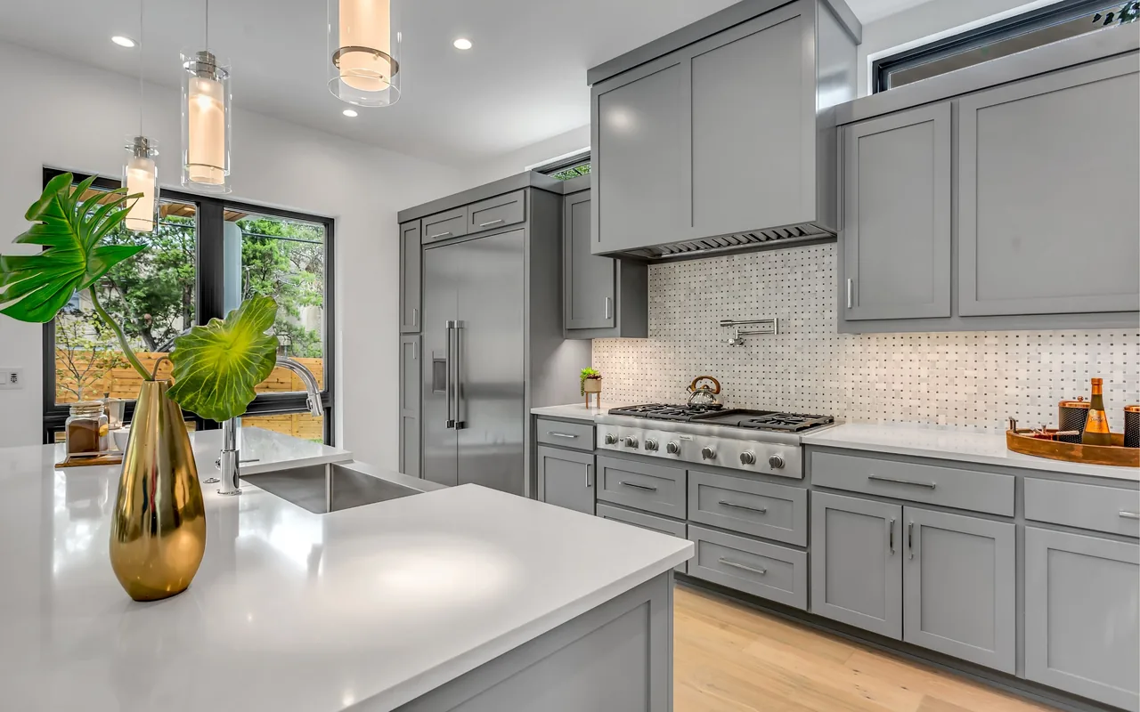 Remodeled kitchen with gray cabinets, island, and tile backsplash