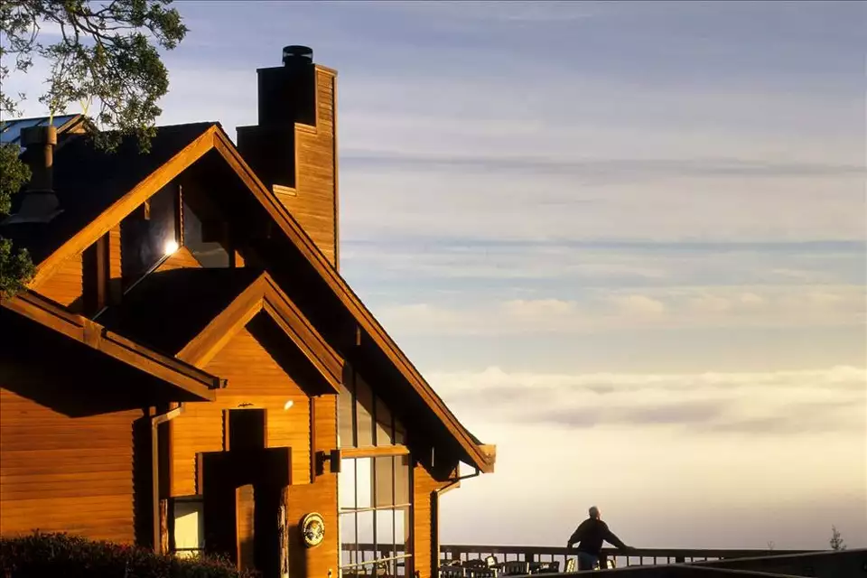 The Mountain Home Inn perched on the ridge of Mount Tamalpais, bathed in warm golden light with a sea of clouds stretching to the horizon