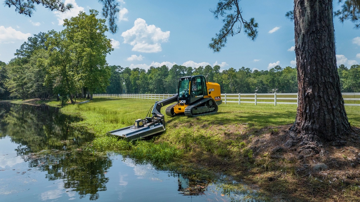 JCB skid steer clearing overgrown brush on a commercial lot in Troy, IL