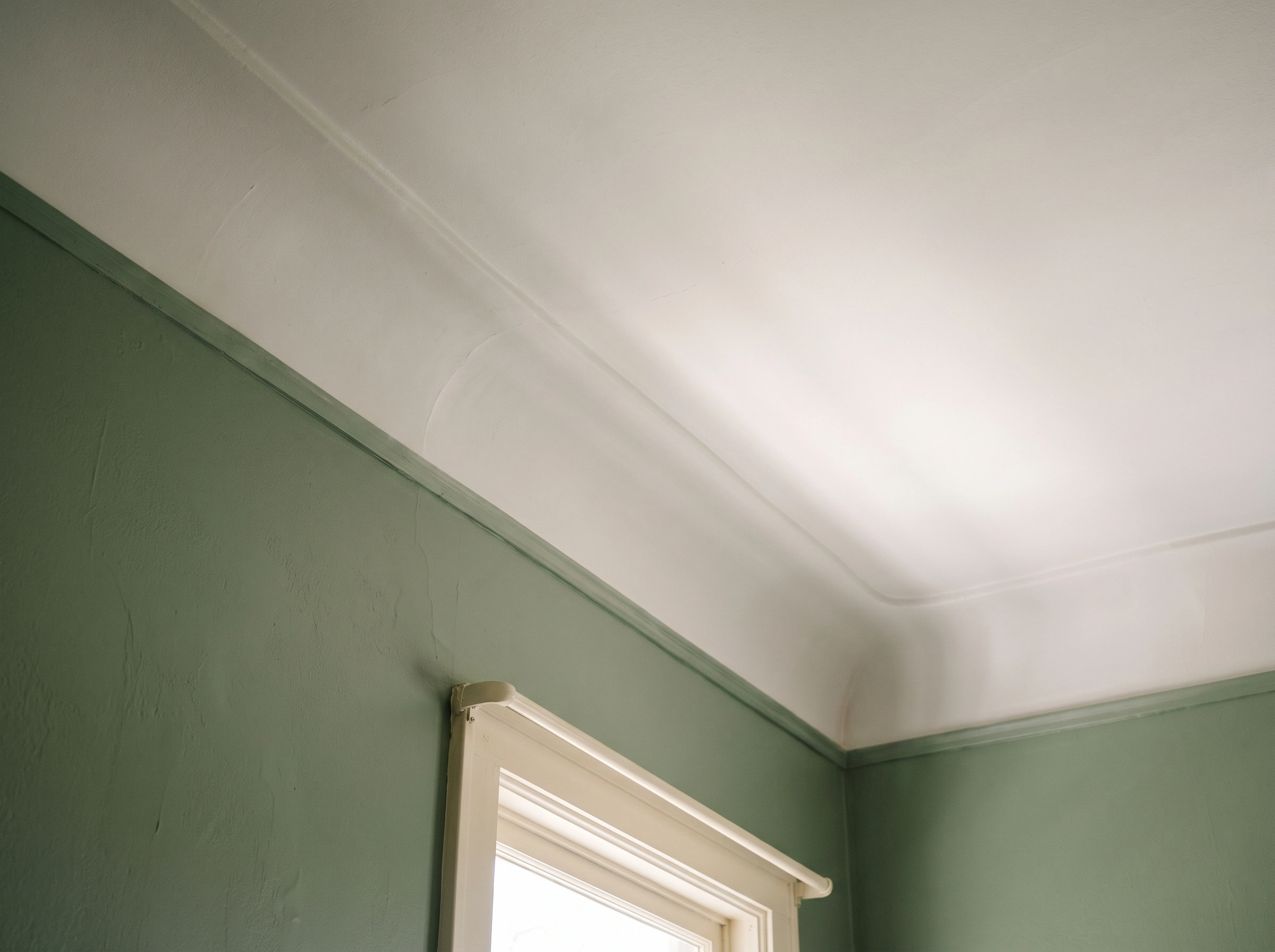 upward-angle photo of a low-sheen ceiling in an older Kirkwood bedroom with coved edges, walls painted muted rosemary, and trim painted soft linen