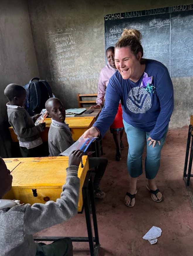 Handing a child a pencil case in Kenya