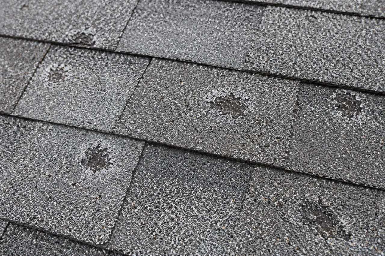 close view of weathered asphalt shingles with impact-like marks