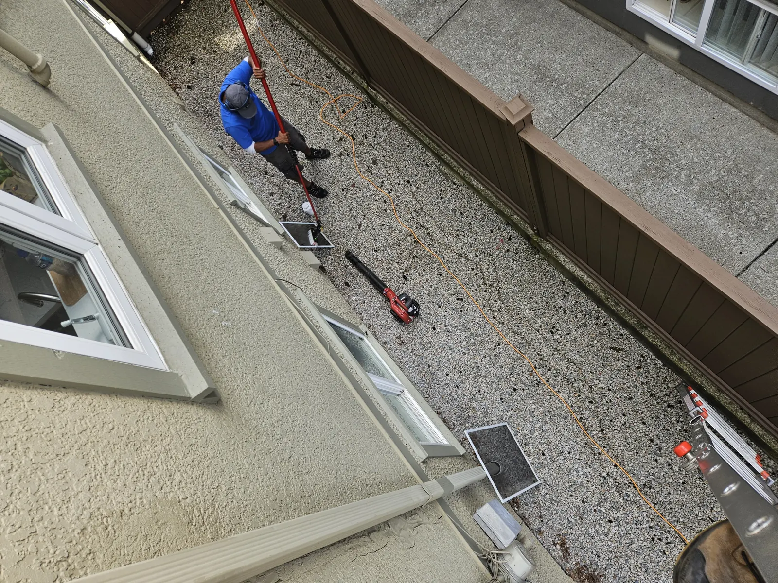Wells crew clearing debris from a flat gravel roof in Metro Vancouver