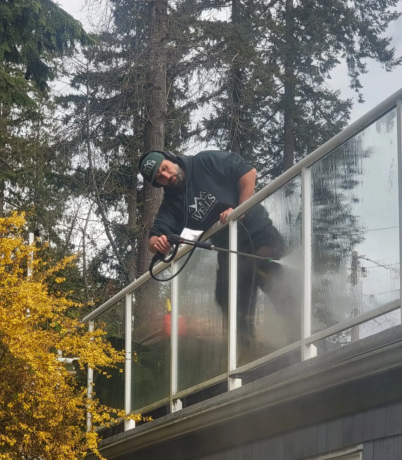 Devin Wells pressure washing a glass deck railing in Metro Vancouver