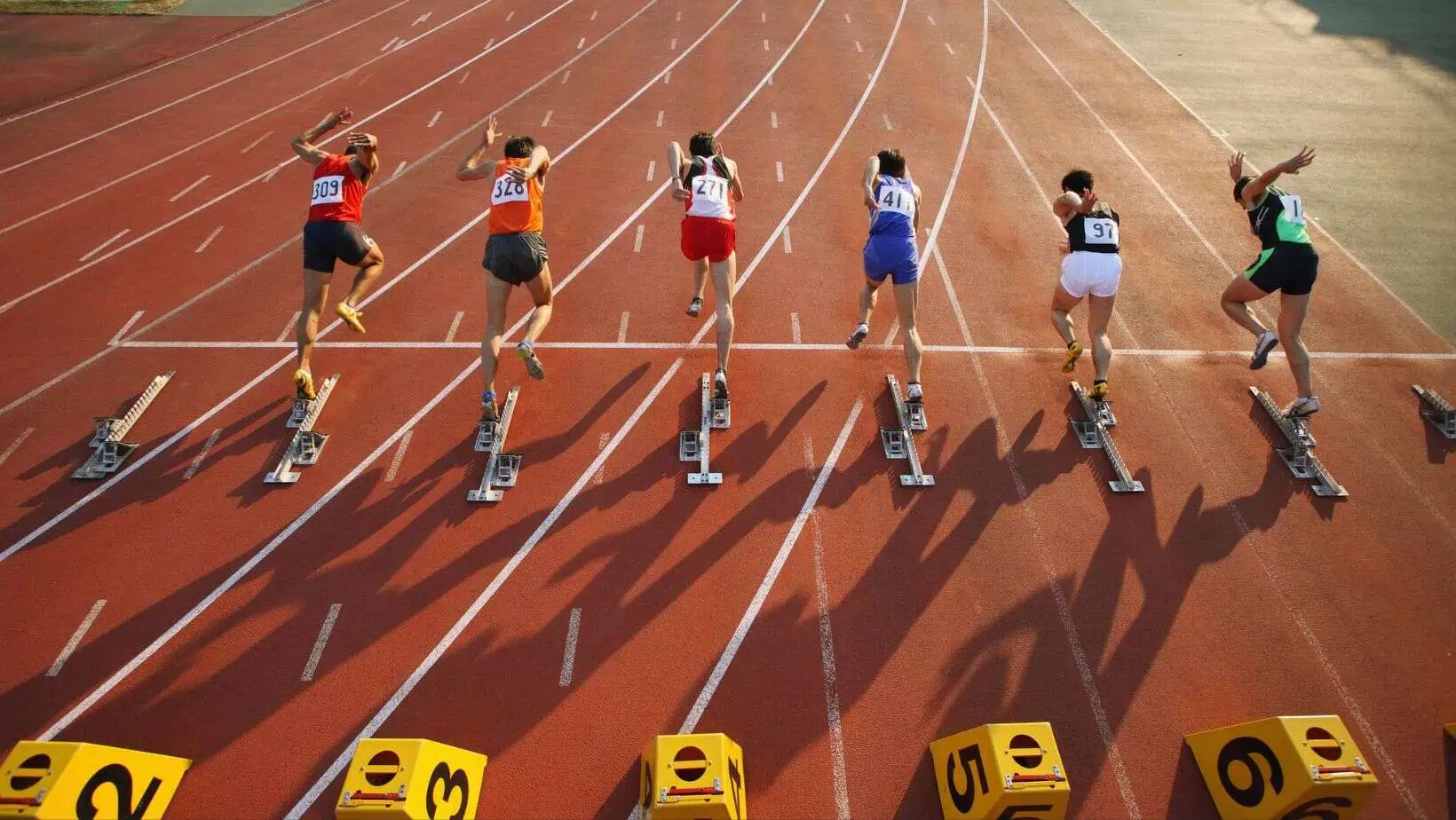 Läufer sprinten los auf Leichtathletikbahn