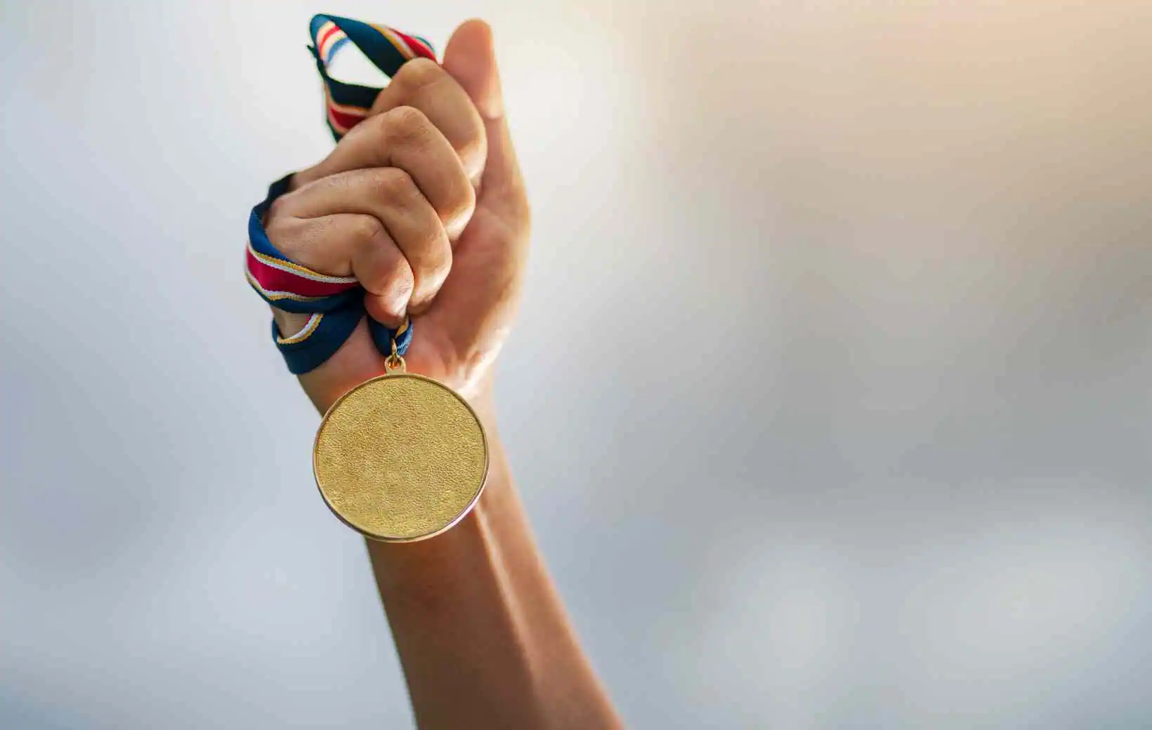 Hand hält eine Goldmedaille. Hand hält eine Goldmedaille.
