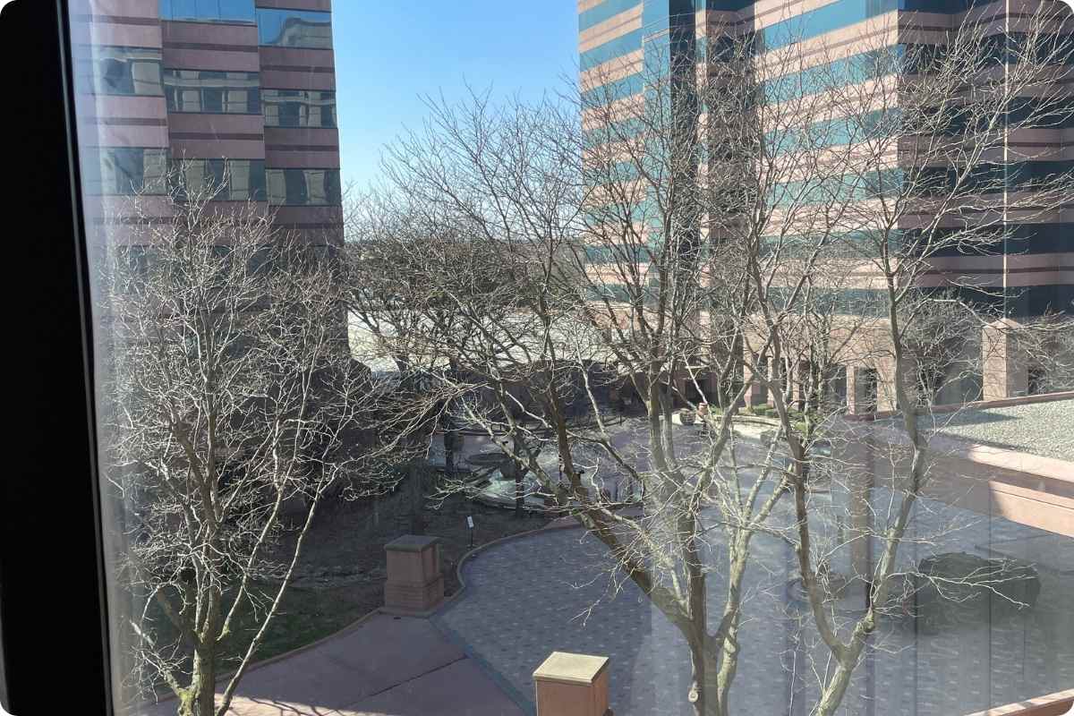 Ausblick auf Parkplatz und Bürogebäude aus Fenster.