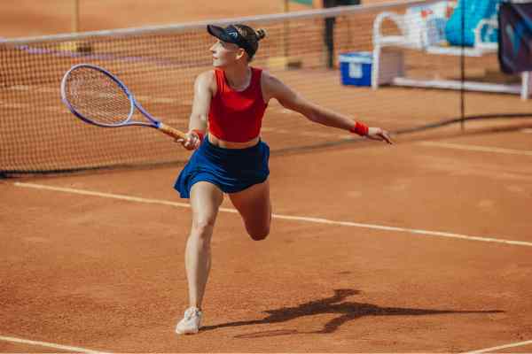 Tennisspielerin läuft mit ienem Lächeln zum Ball.