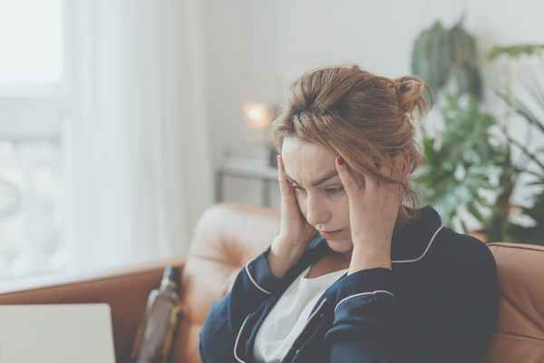 Mutter sitzt auf Sofa und hält sich verzweifelt die Schläfen. Mutter sitzt auf Sofa und hält sich verzweifelt die Schläfen.