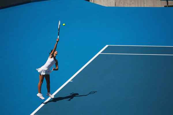 Tennisspielerin streckt sich, um Ball zu bekommen. 