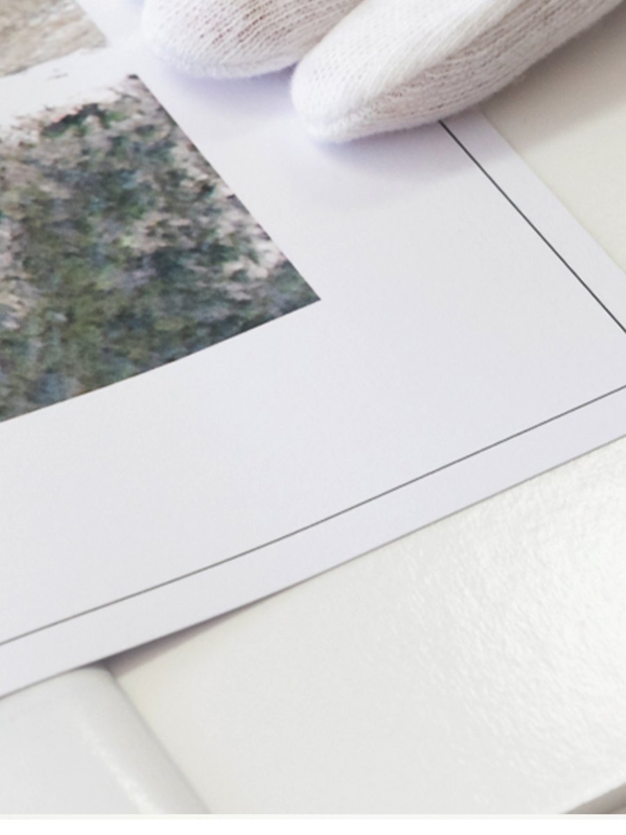 A fine art print being handled with cotton gloves
