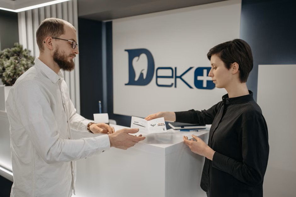 Paperwork being handed across a dental front desk