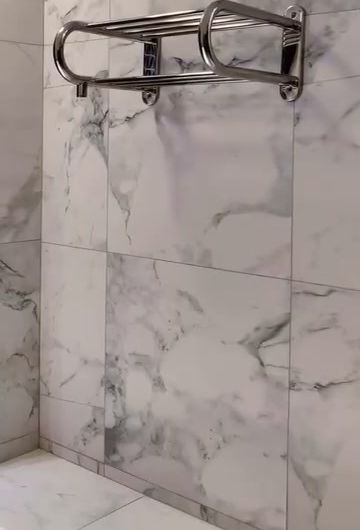 Toallero eléctrico de acero en un baño revestido símil mármol