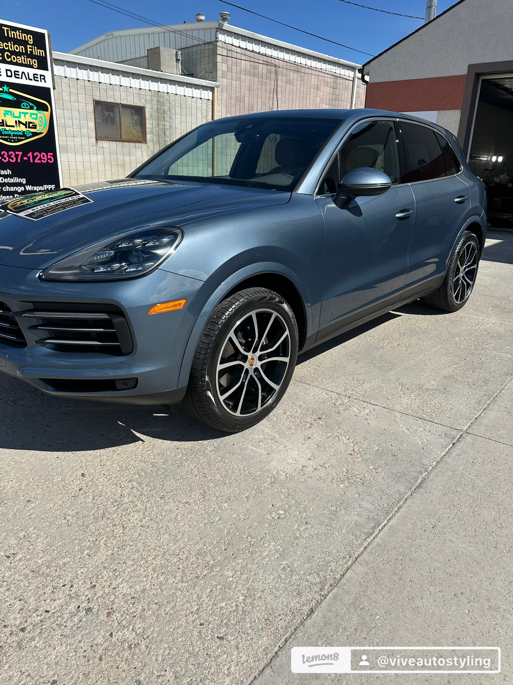 Gray luxury SUV parked outside VIVE Auto Styling, showcasing precision-installed Paint Protection Film (PPF) and high-gloss finish, with a sign promoting automotive detailing services in Casper, WY.