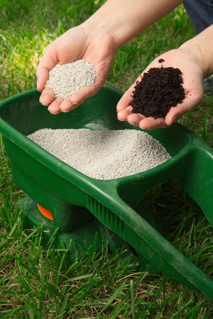 a person holding fertilizer and dirt in a wheelbarrow