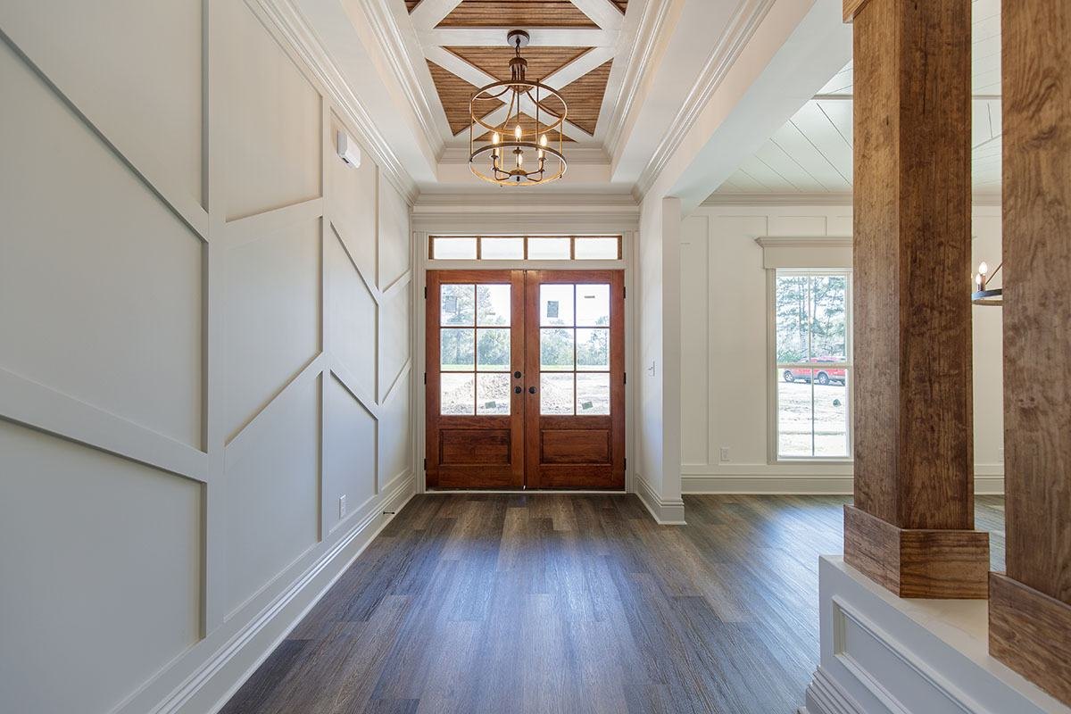 Foyer with a wood-beamed ceiling, board-and-batten walls and wood double doors