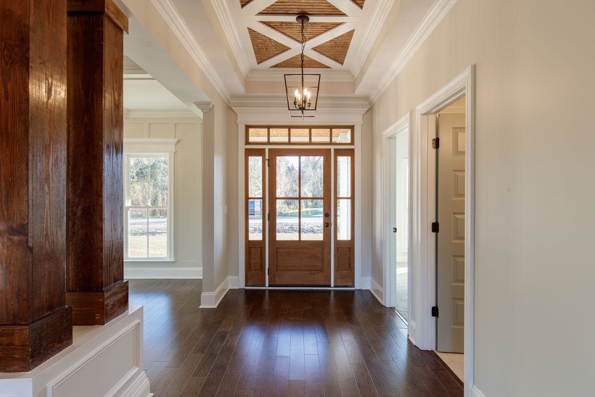 Foyer with cedar columns, paneled walls and a beamed ceiling