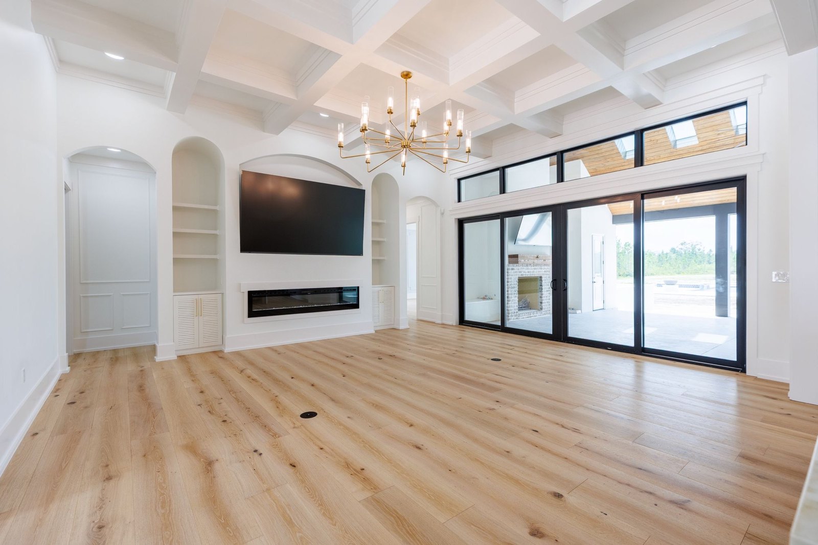 Living room with a coffered ceiling, arched niches and a brass chandelier