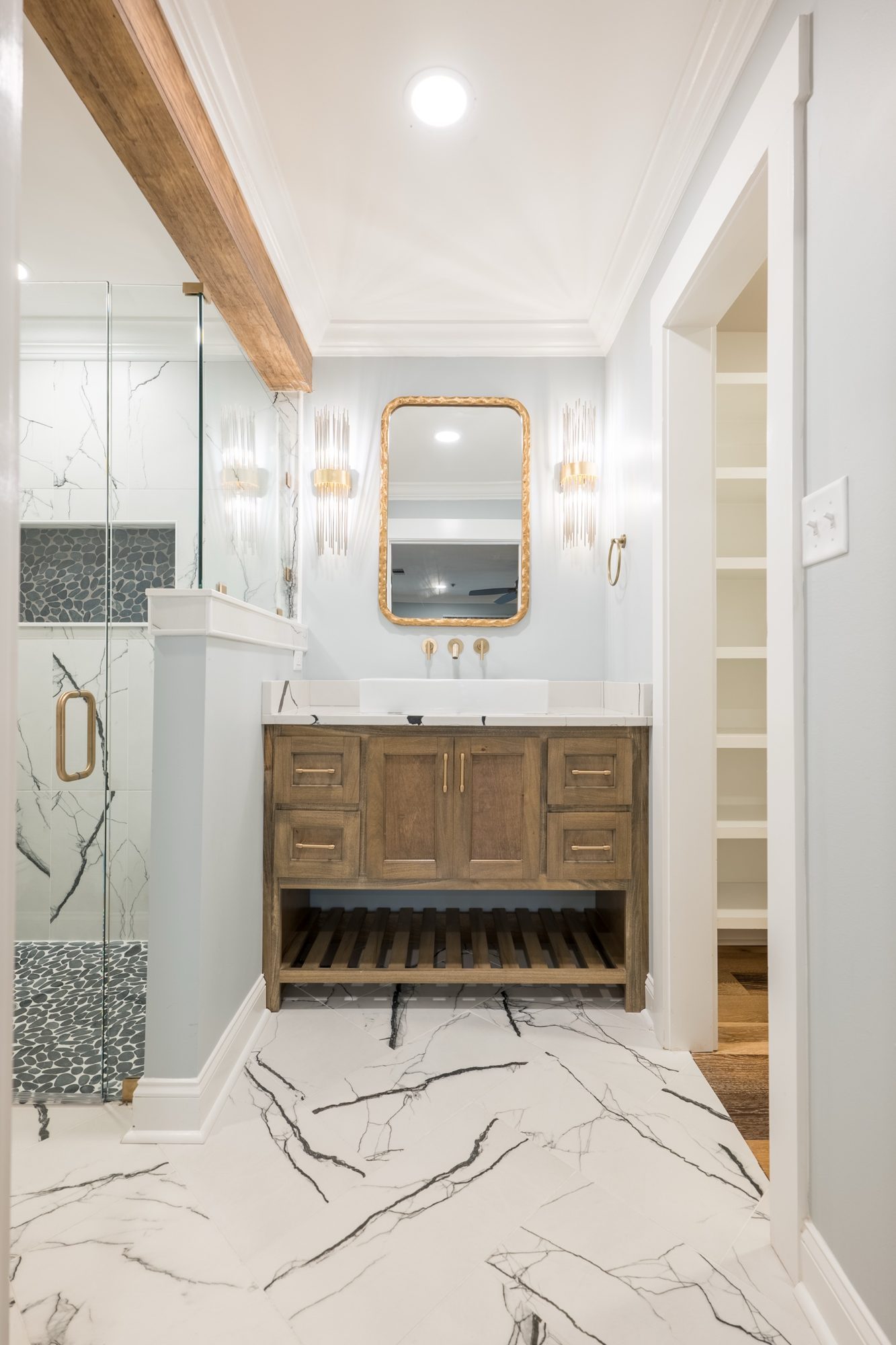 Renovated bath with a walnut vanity and gold mirror