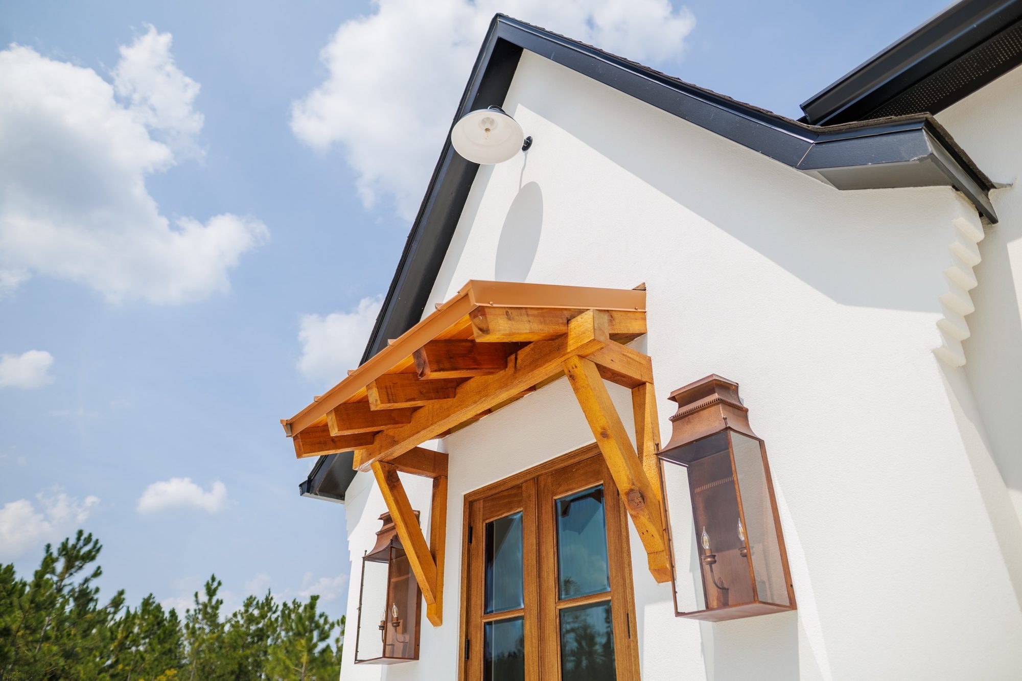 Cedar awning and copper lanterns against a blue sky
