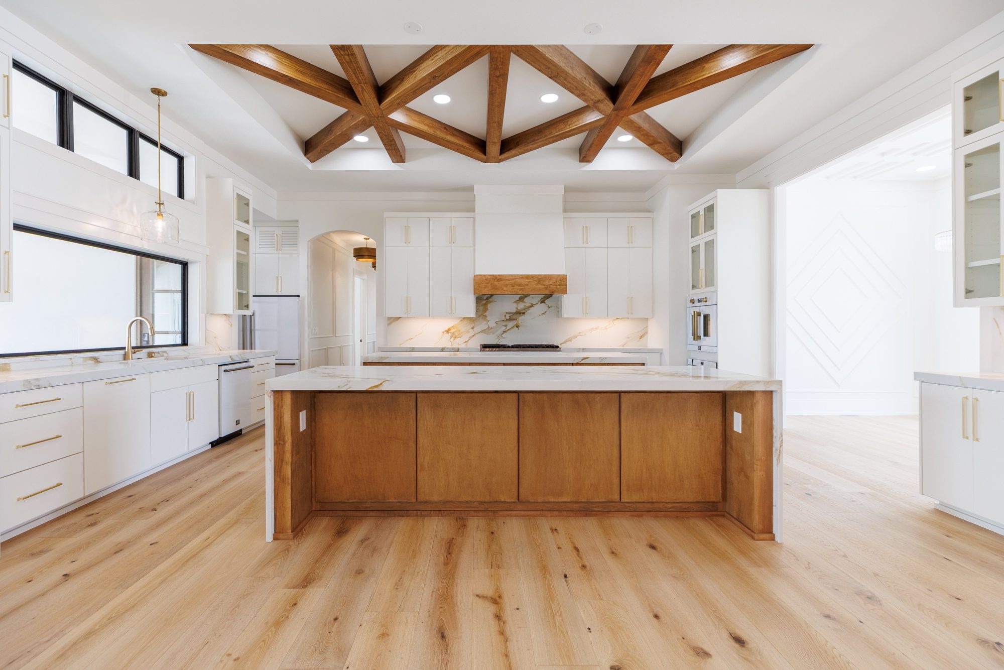 Kitchen with a waterfall island under a starburst of wood beams