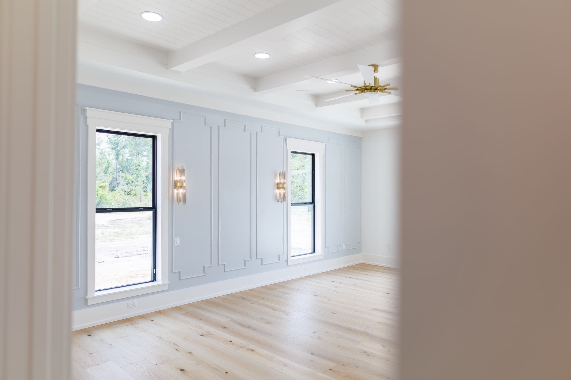 Bedroom with a picture-frame paneled wall and a coffered ceiling