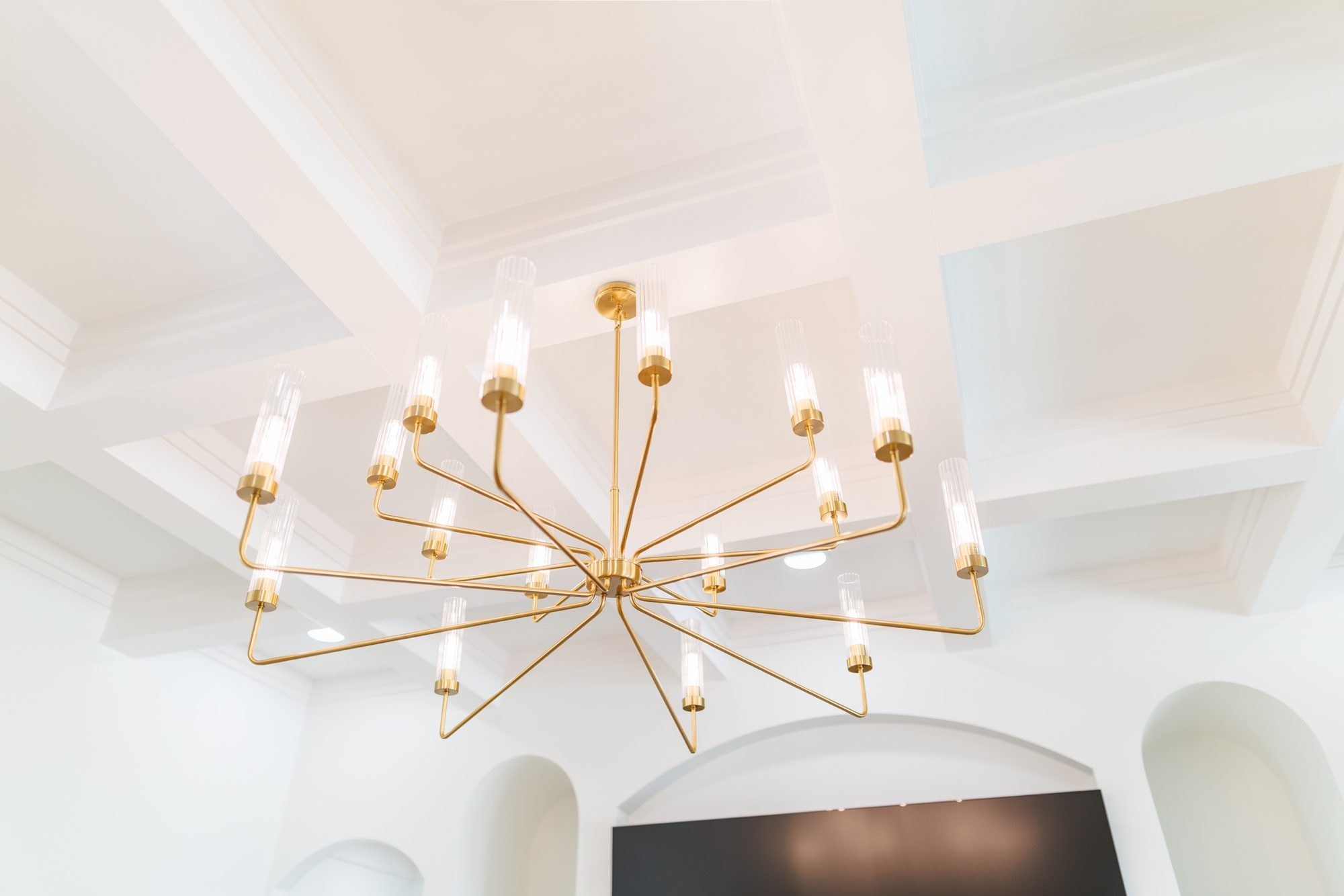 Brass chandelier under a white coffered ceiling