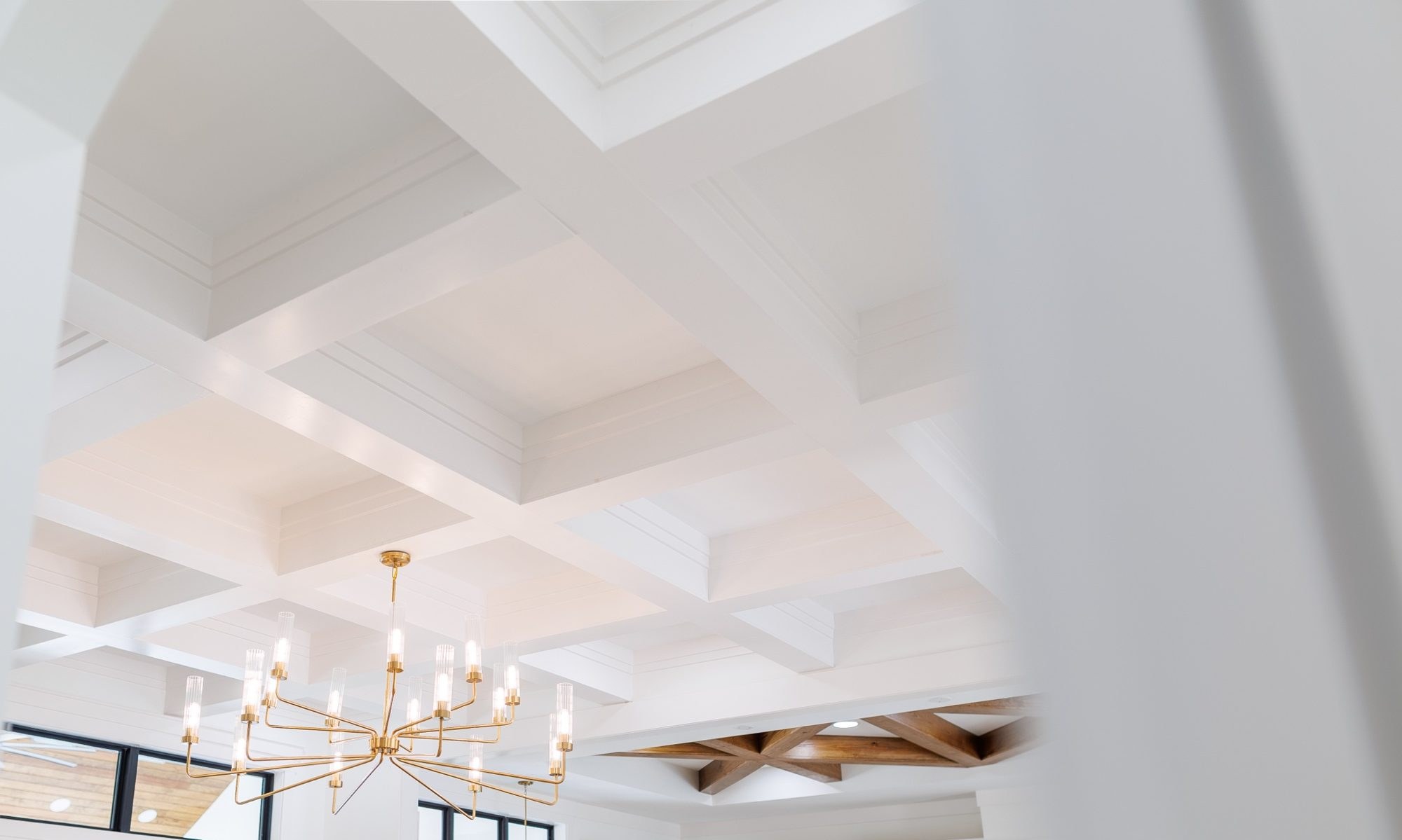 Coffered ceiling with stained wood beams and a brass chandelier