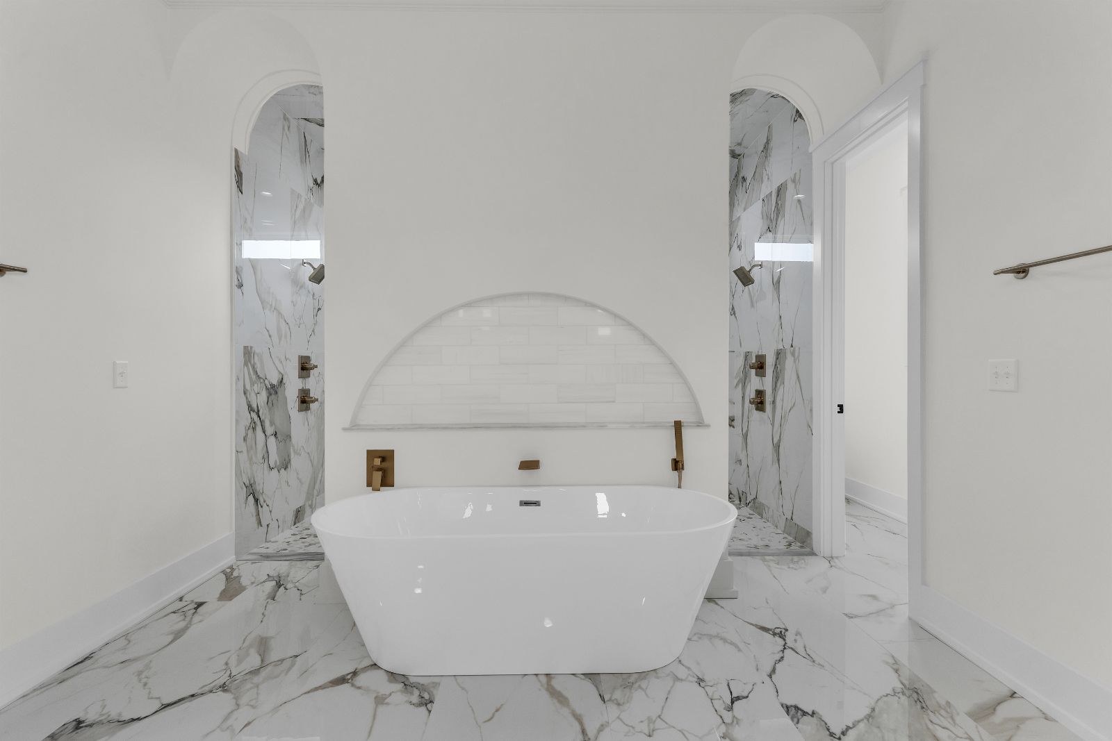Primary bath with a freestanding tub in an arched marble niche