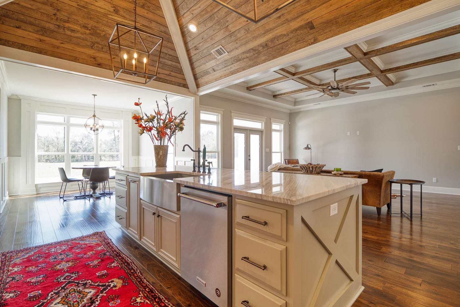 Kitchen with a farmhouse island and a red rug under a vaulted wood ceiling