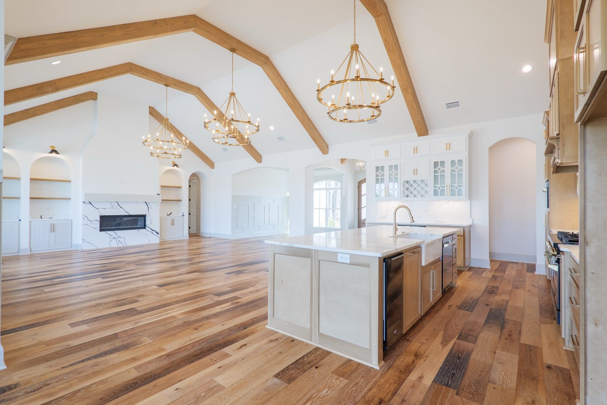 Kitchen open to the great room under a vaulted ceiling with wood beams