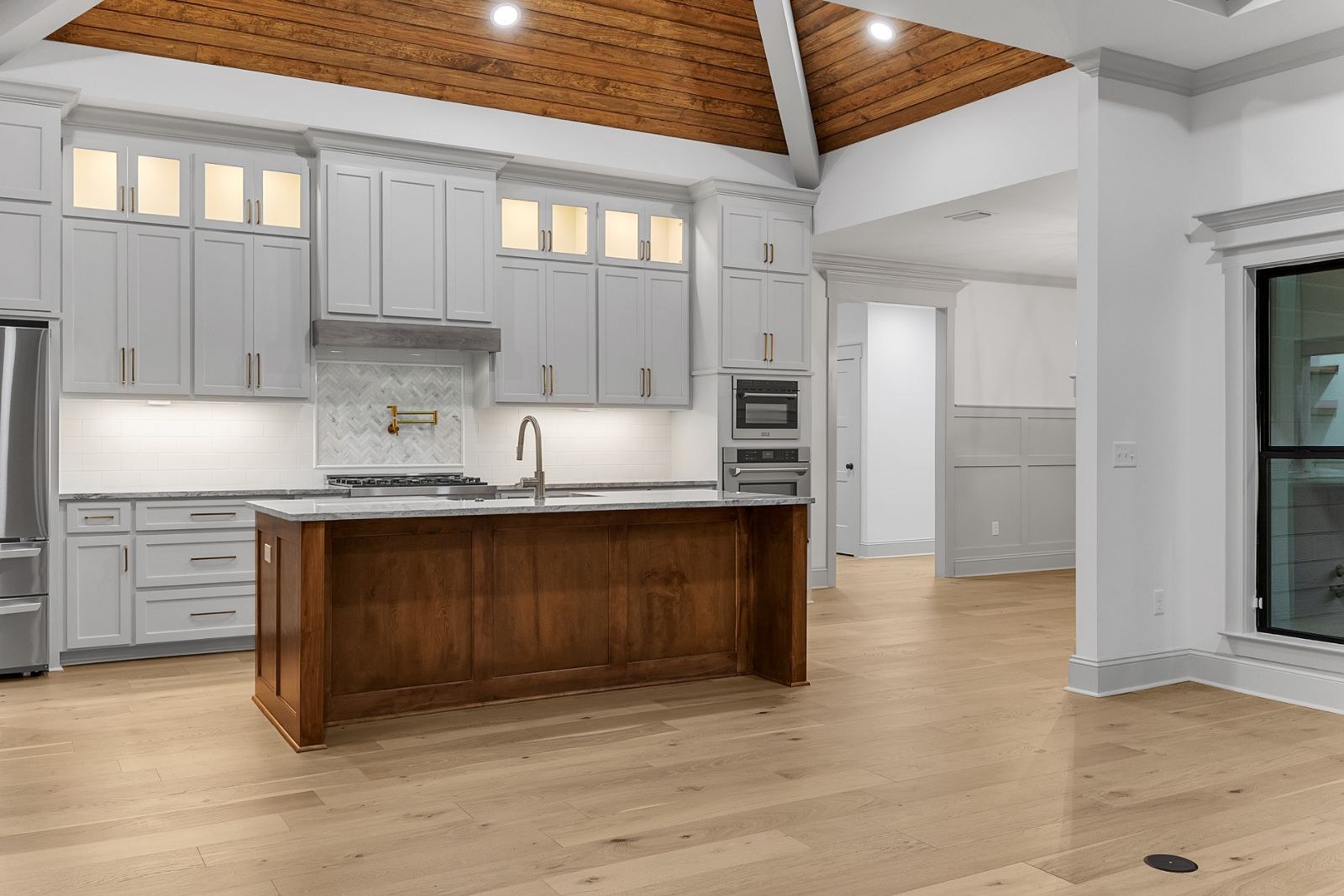 Kitchen with a stained wood island, gray cabinets and a vaulted wood ceiling