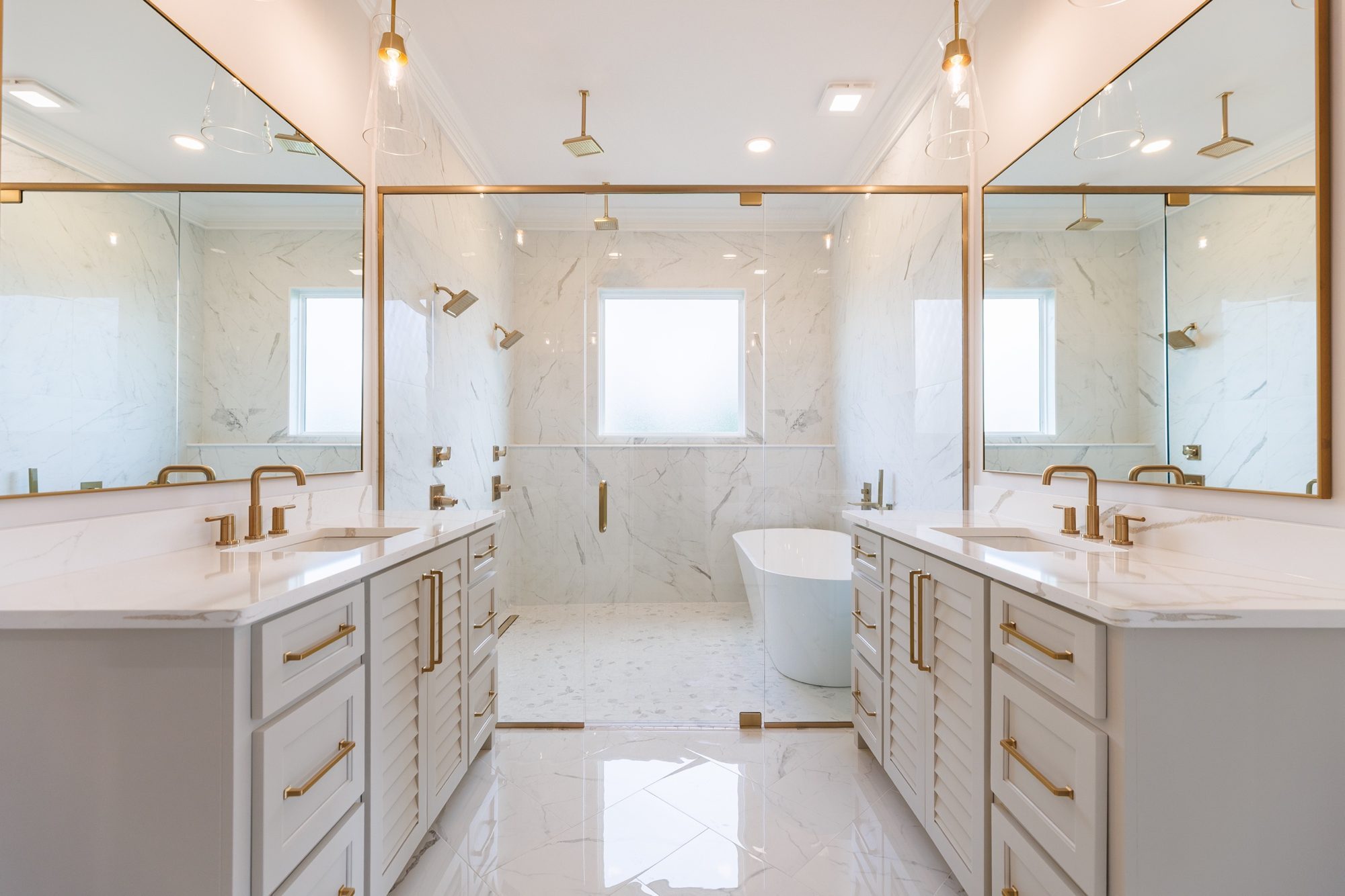 Primary bath with twin louvered vanities and a glass wet room with a freestanding tub