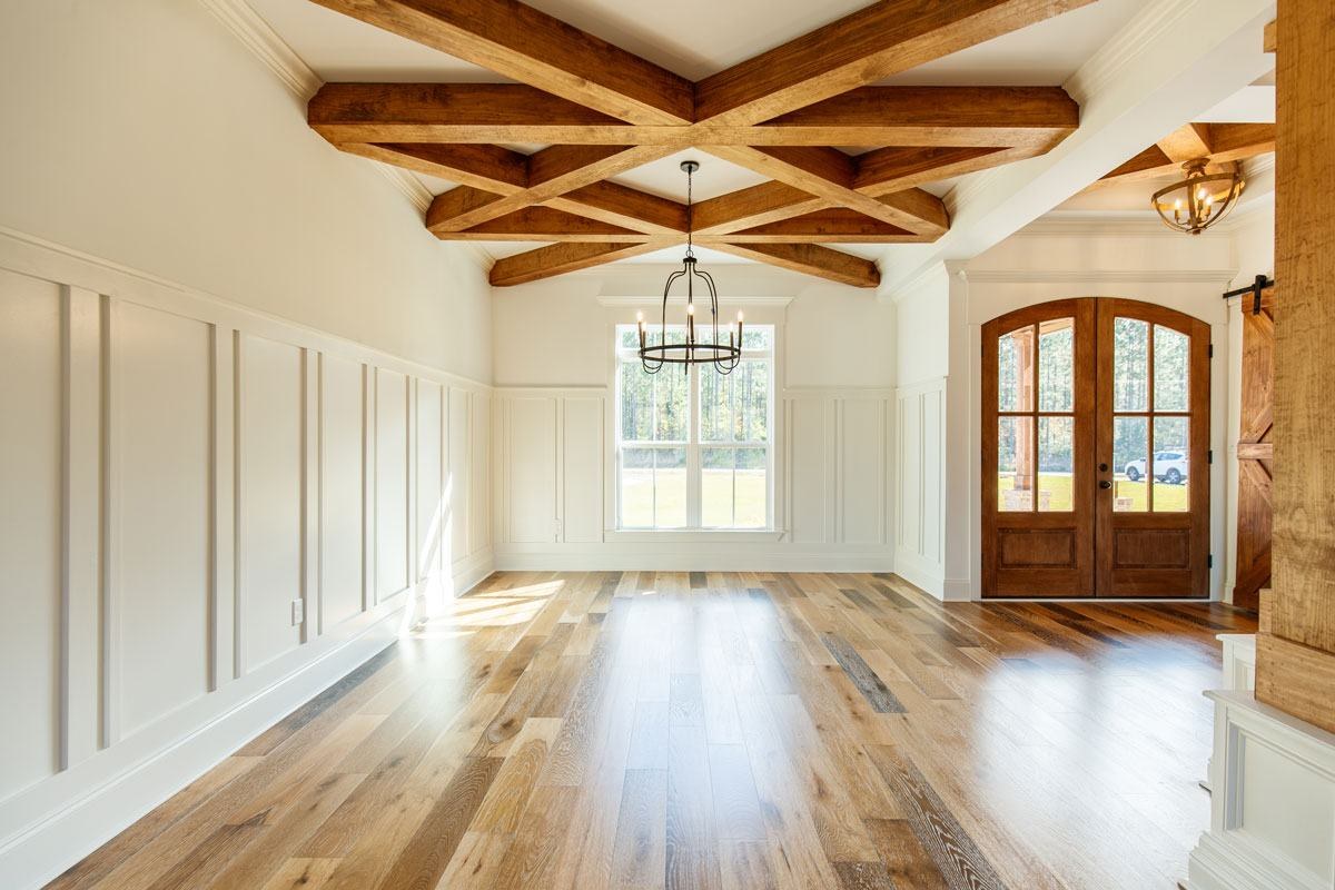 Dining room with a wood-beamed ceiling, board-and-batten walls and arched front doors