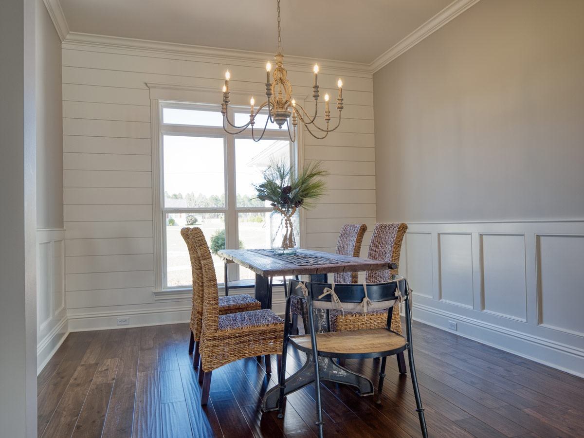 Dining room with shiplap and wainscoting under a chandelier