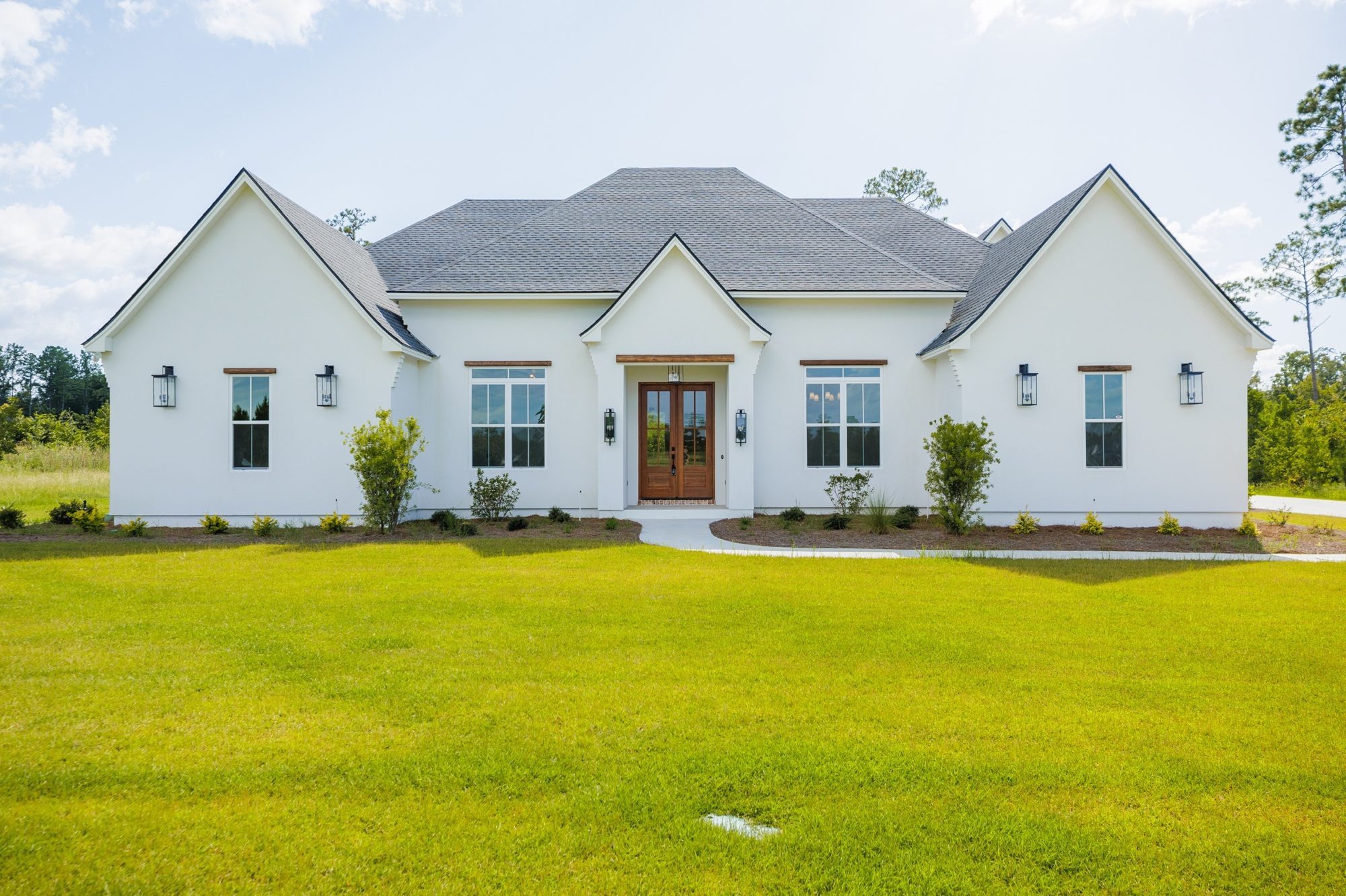 Front of a white LaCatalina home with wood double doors and copper lanterns