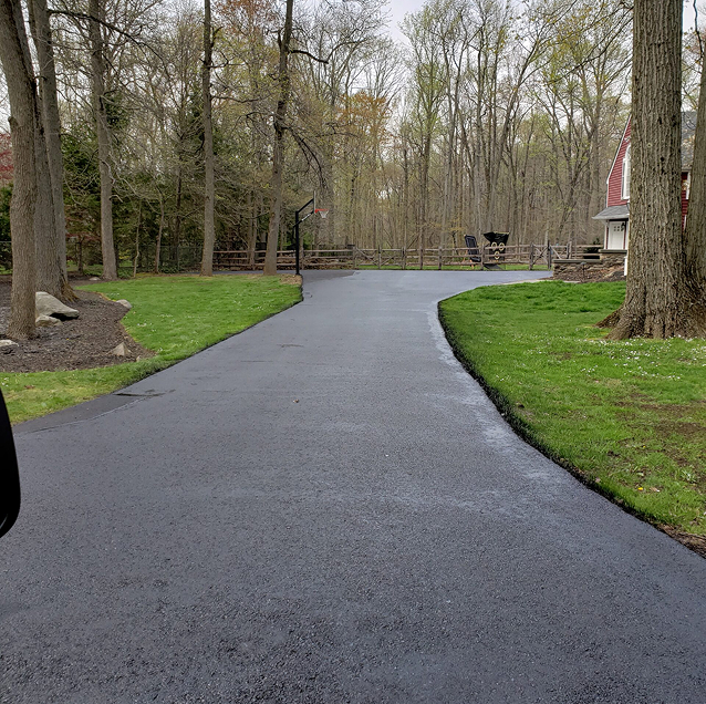 Long curved residential driveway with a fresh black sealcoat finish in Gloucester County, NJ