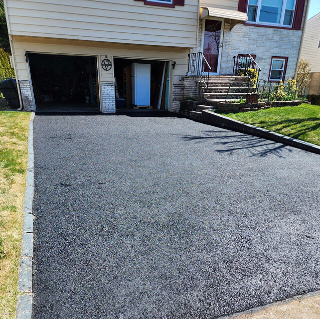 Wide two-car asphalt driveway with a cobblestone paver border and fresh finish